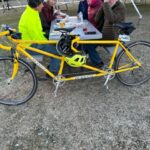 A group of people sitting at a table with a bicycle

Description automatically generated with medium confidence